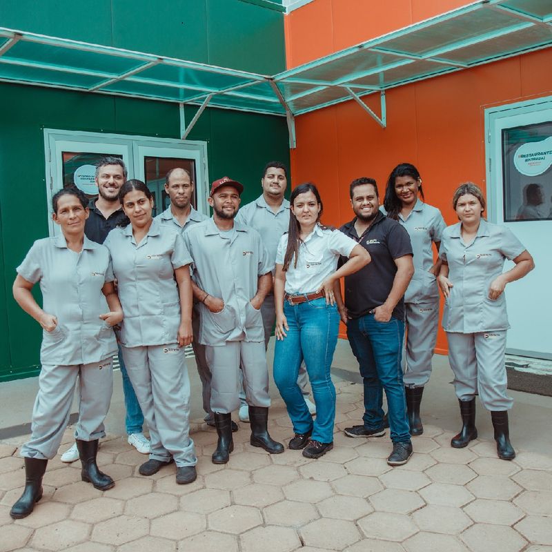 Equipe multifuncional do Grupo Distrital reunida em frente a uma unidade atendida