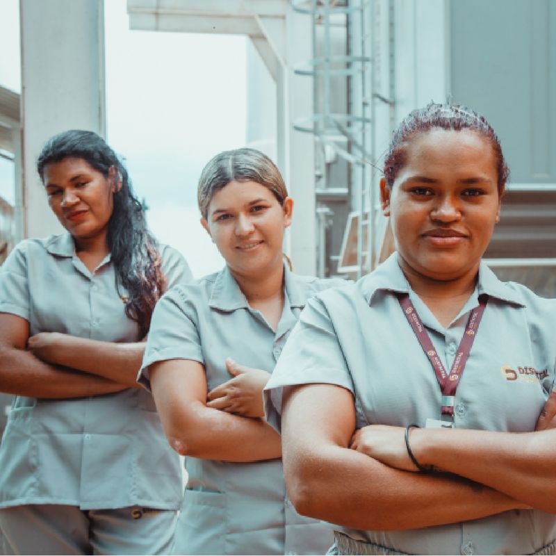 Três colaboradoras uniformizadas do Grupo Distrital em ambiente industrial