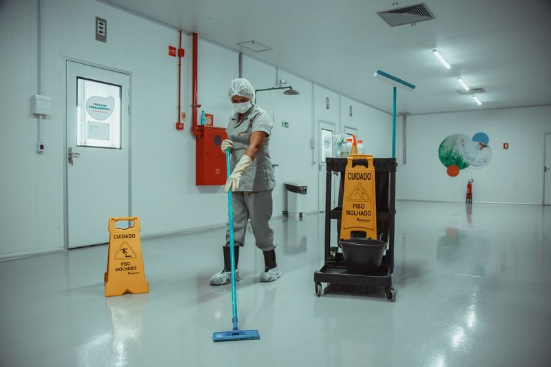 Profissional de limpeza do Grupo Distrital com EPI completo higienizando ambiente hospitalar