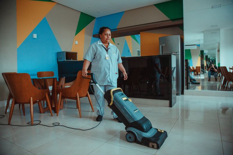 Profissional de limpeza cuidando de salão de festas com aspirador profissional
