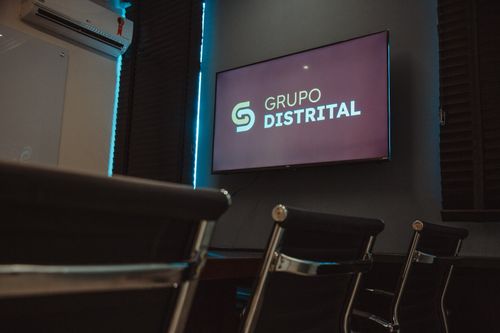 Sala de treinamento da sede com a marca Grupo Distrital em tela